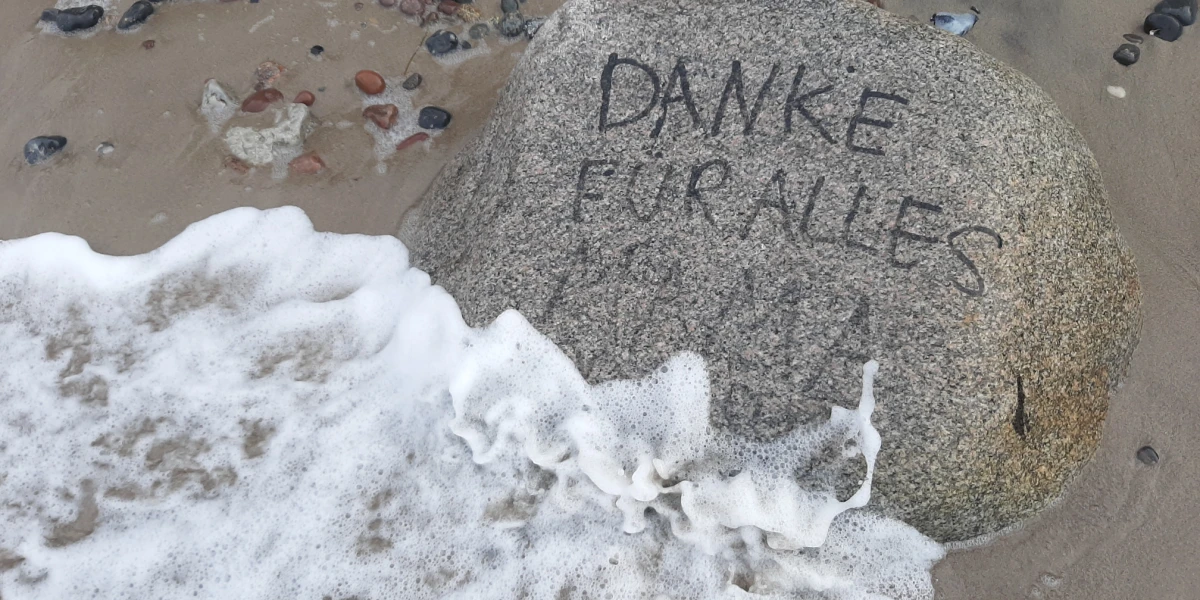 Beschrifteter Stein am Meeresstrand „Danke für alles Mama“