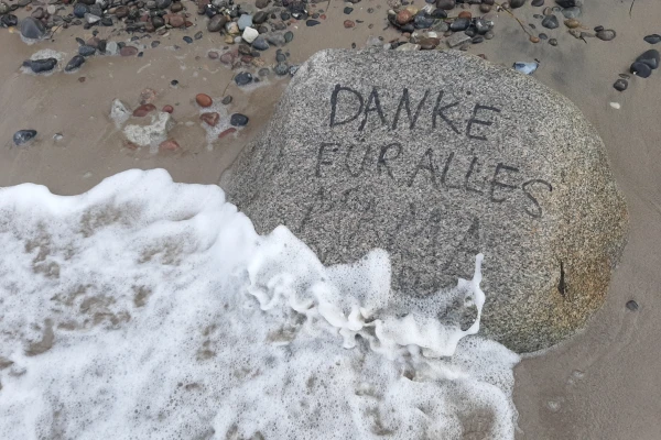 Beschrifteter Stein am Meeresstrand „Danke für alles Mama“